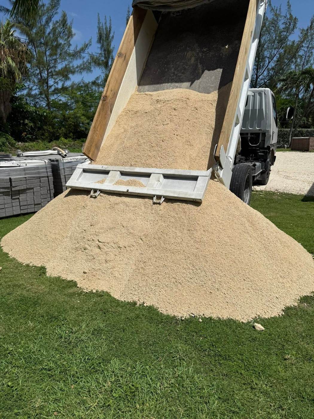 Dump truck delivering and pouring fill sand on a Grand Cayman property